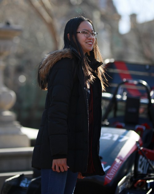 Jin poses with electric race car outside of College Hall