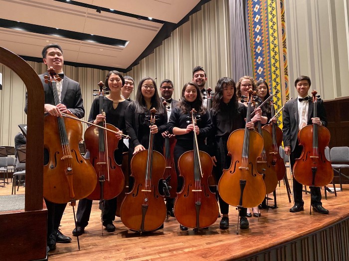 Melanie Hilman and orchestra pose in concert attire with instruments