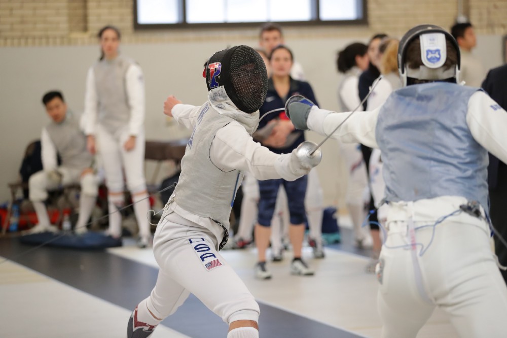Jerry Wu in fencing gear spars with opponent 