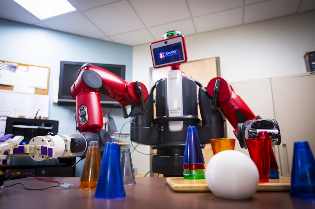 A red humanoid robot manipulates and stacks cones of various colors.