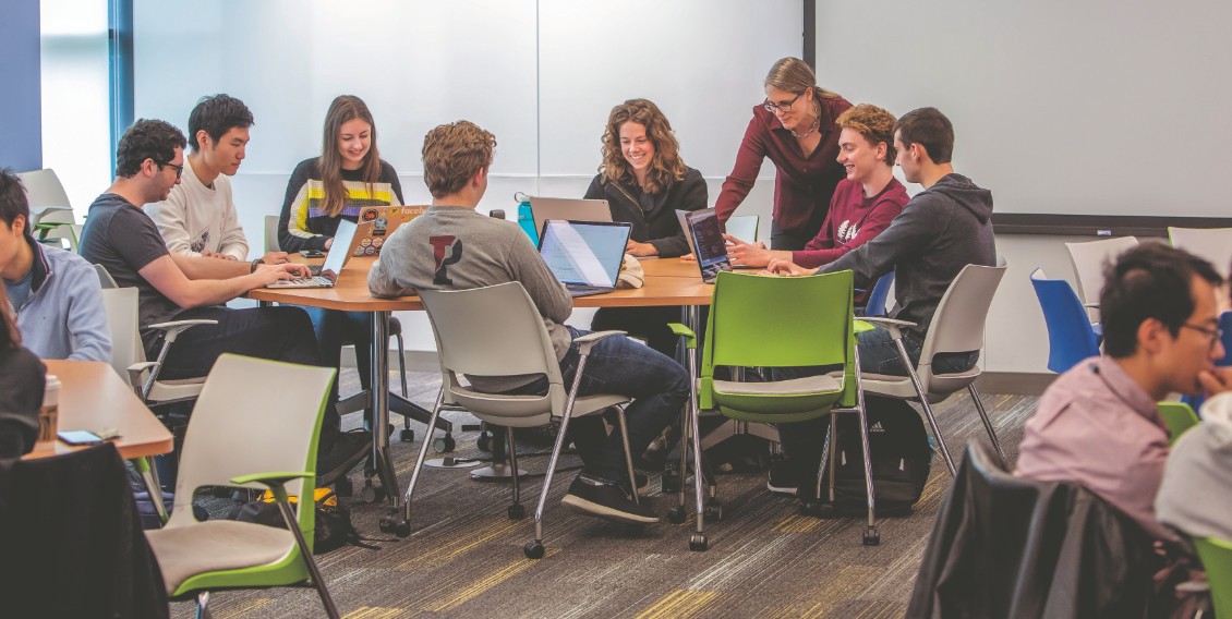 Stephanie Weirich standing behind a group of students working around a circular table.