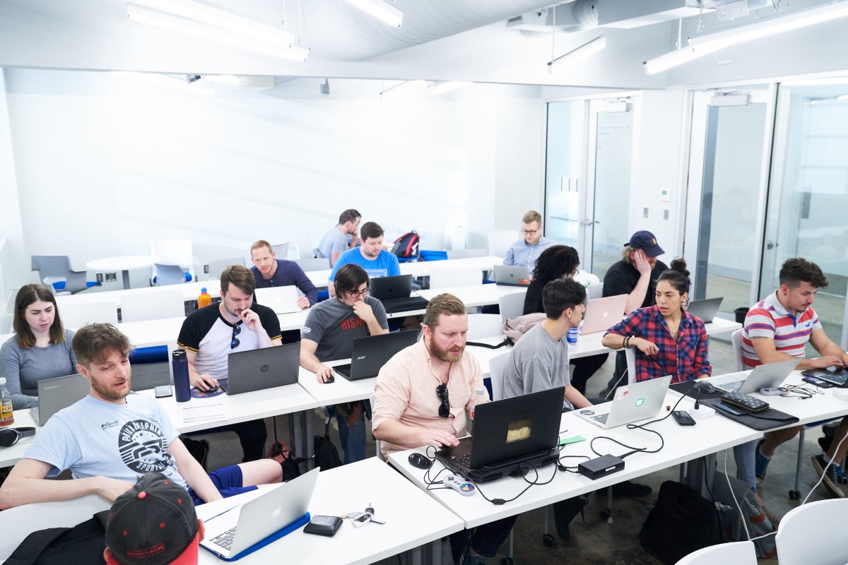 Penn LPS Coding Boot Camp students working on laptops in a brightly lit classroom.