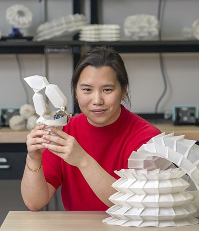 Cynthia Sung holds up white origami robot