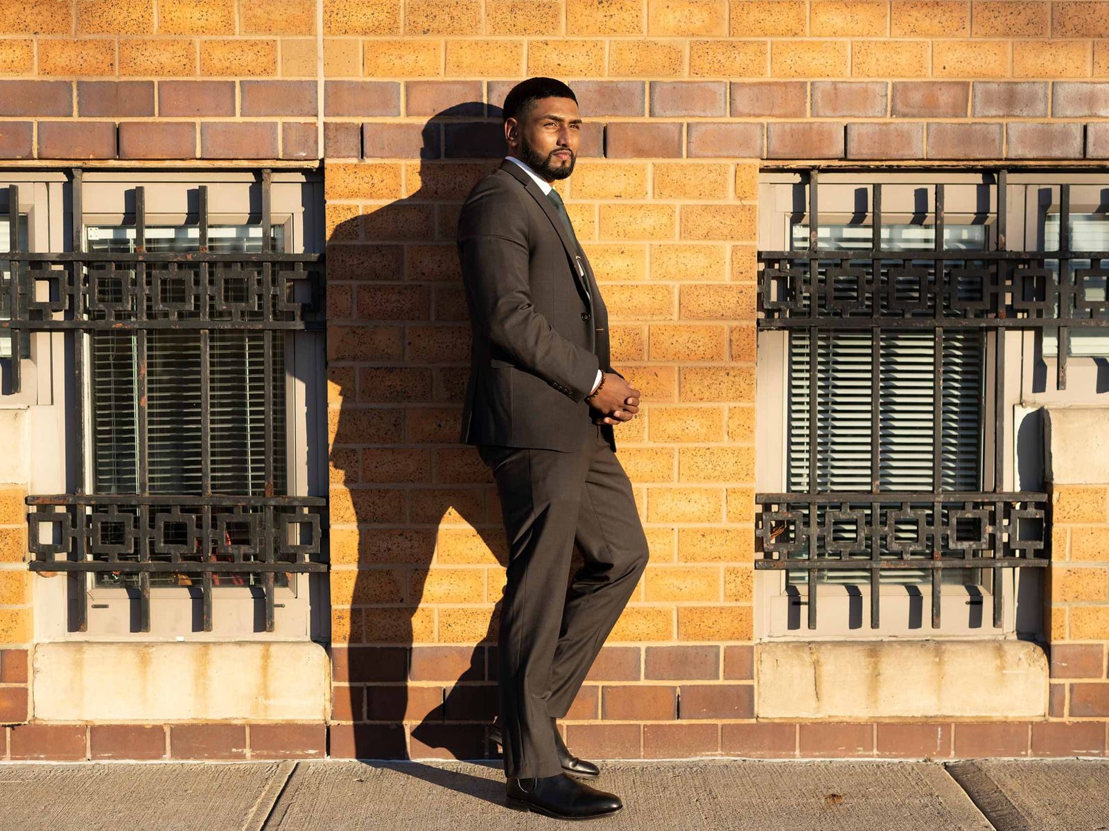 Kris Sidial, wearing a suit, stands against building on a New York City sidewalk.