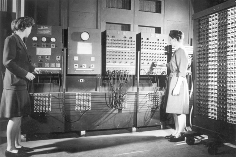 An archival photo of two women, Jean Bartik and Frances Spence, operating the ENIAC’s main control panel, a massive, complicated array of dials and wires.