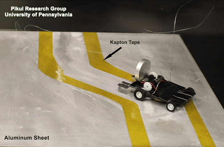 A "metal-eating" robot autonomously navigates a path marked by non-conductive tape on either side of it.