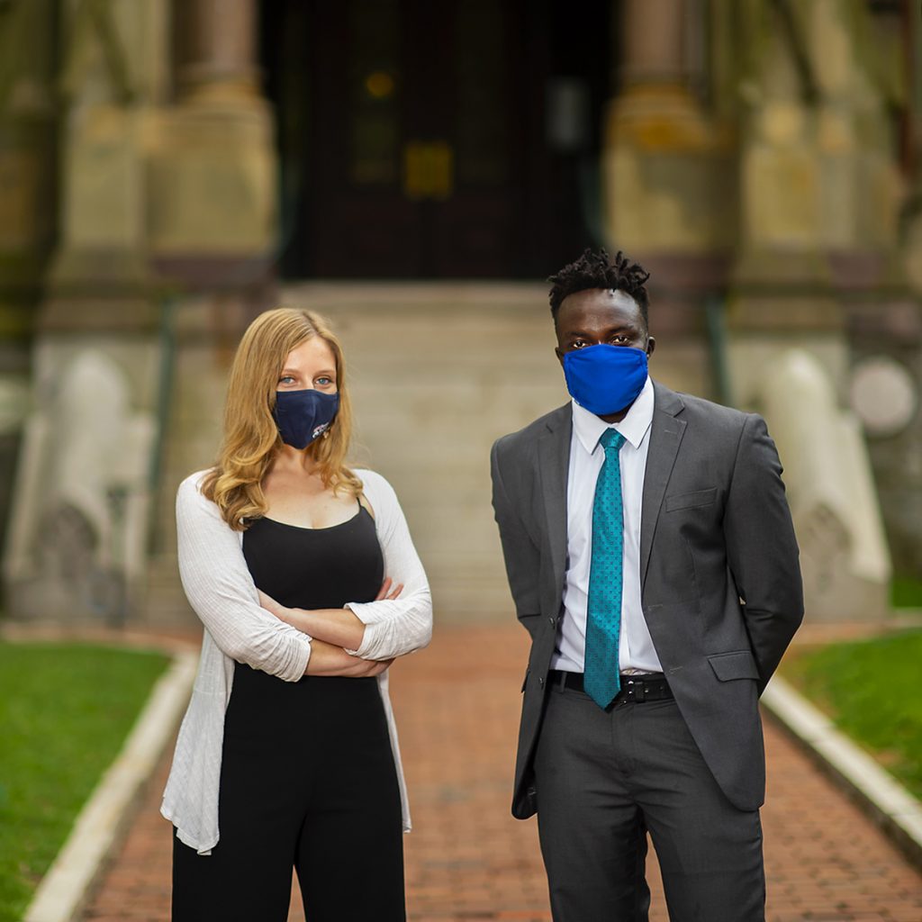 Leah Voytovich and Martin Leet stand in facemasks in front of College Hall. 