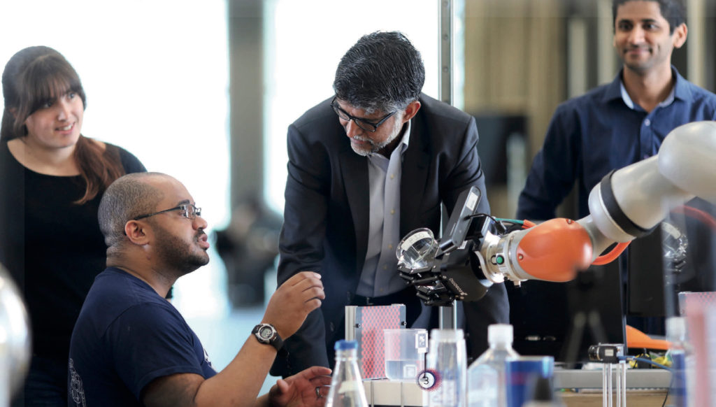 Dean Vijay Kumar works on a robotic arm with students