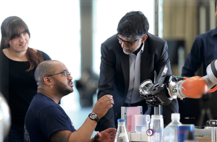 Dean Vijay Kumar works on a robotic arm with students