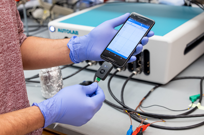 Close up gloved hands plugging a RAPID test into a smartphone.