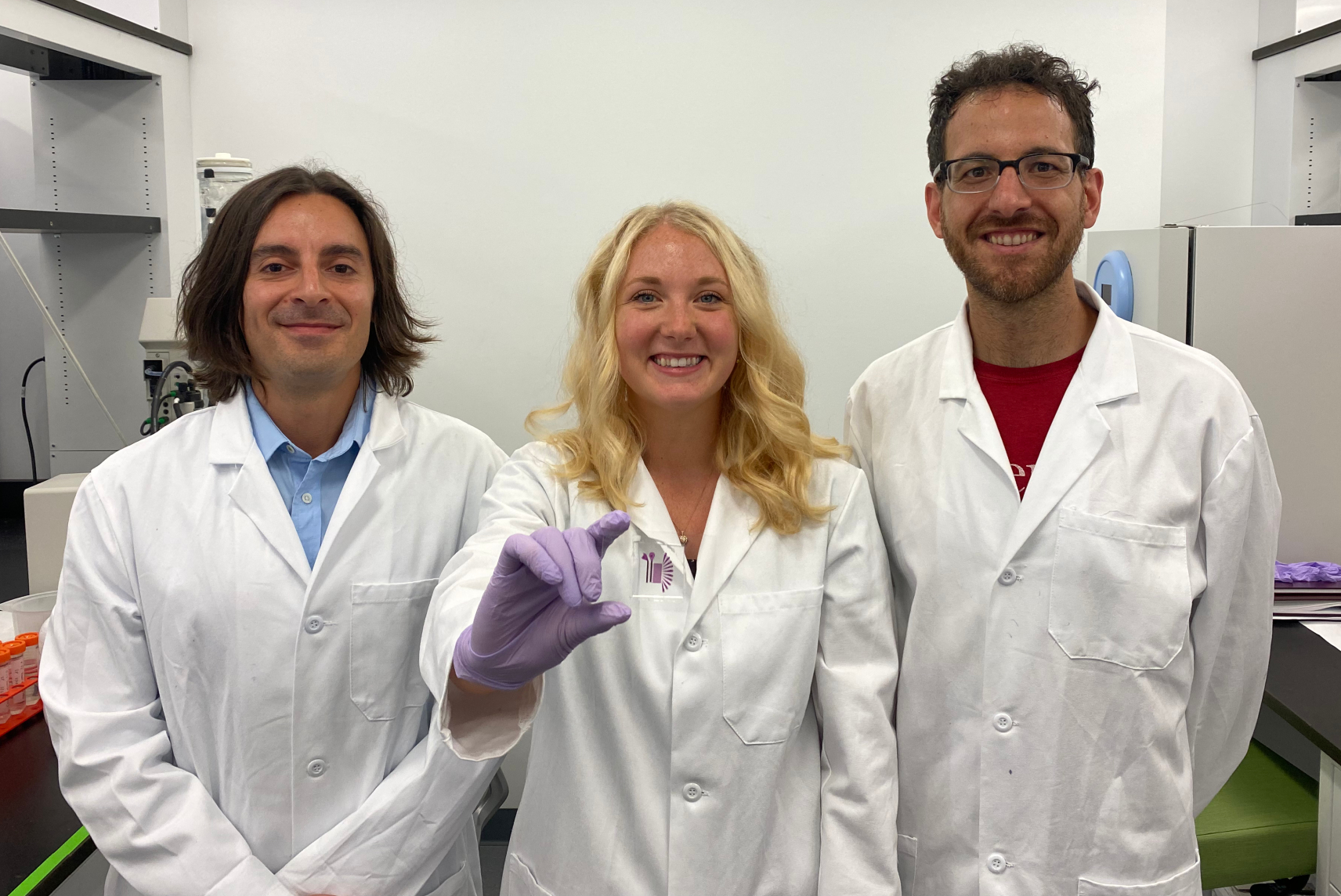 Wearing lab coats, Michael Mitchell, Sarah Shepherd and David Issadore pose with their new device.