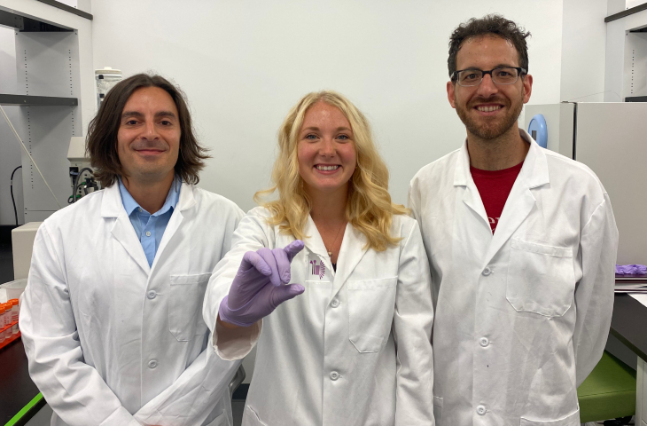 Wearing lab coats, Michael Mitchell, Sarah Shepherd and David Issadore pose with their new device.