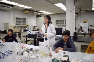 A researcher in a lab coat leads a lecture.