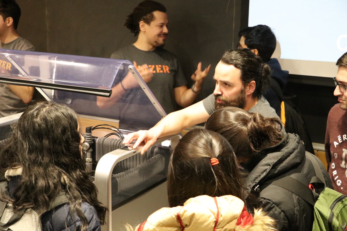 A crowd of students gathers around Wazer's machine.