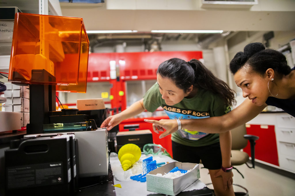 Erynn Johnson and Aja Carer work with a 3D printer