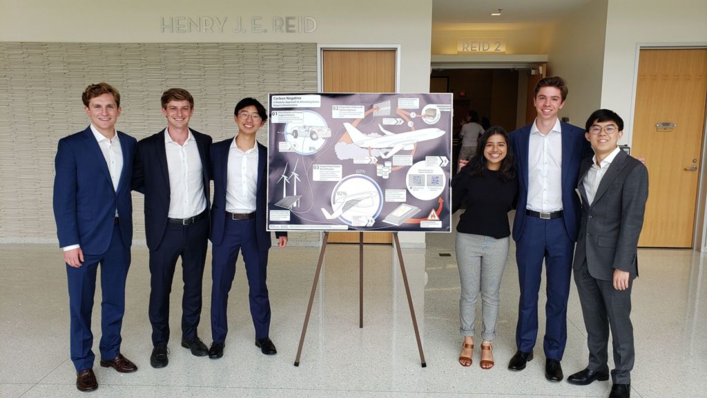 Students pose next to their poster