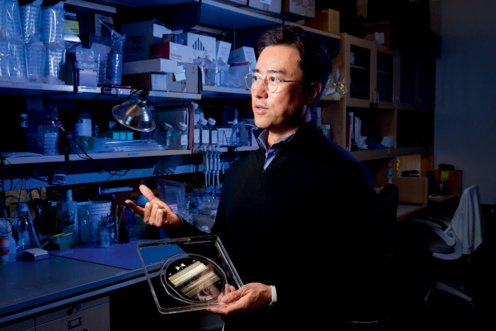 Image of Dan Huh in his lab holding a plastic dish.