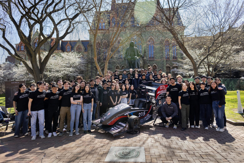 A group of Penn students in front of College Hall posing with the new electric racecar.