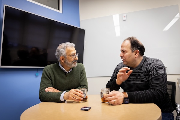 Nader Engheta and Firooz Aflatouni chat animatedly over cups of tea in the latter's office.