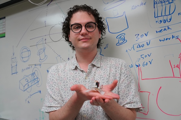 Daniel Fesbach, a Ph.D. student, holds an origami robot