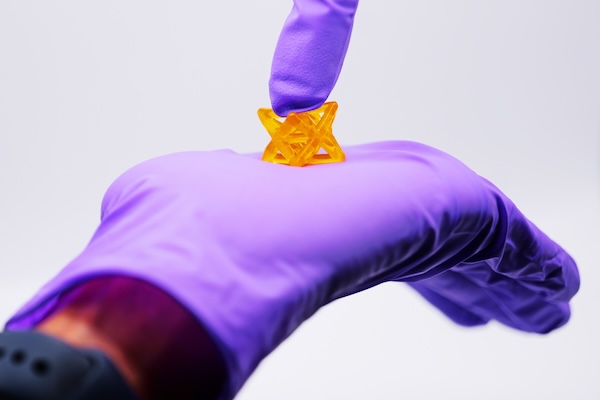 A hand encase in a rubber glove holds a sample of the flexible biomaterial.