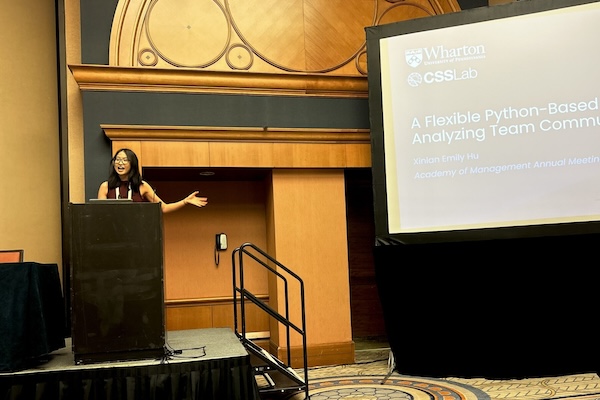 Emily Hu stands onstage at a conference, presenting slides.