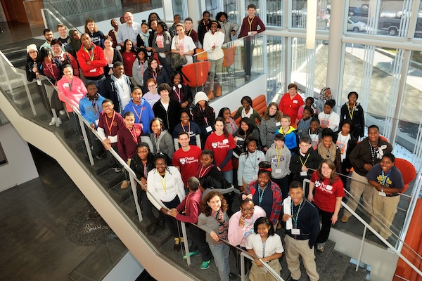 A collection of students and researchers pose on a staircase.