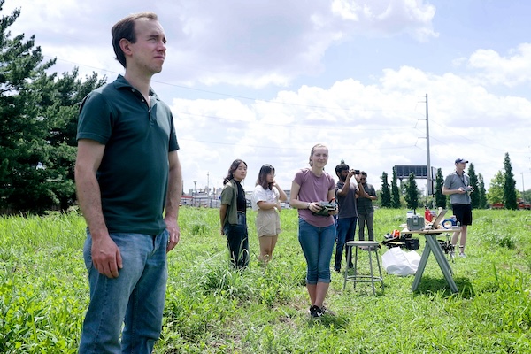 Eric Eaton and several other researchers stand in a field while controlling robots.