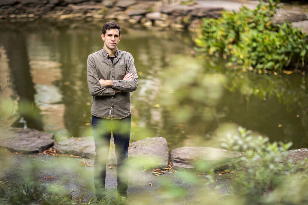 Pictture of faculty member Cesar de la Fuente outside next to a pond of water.