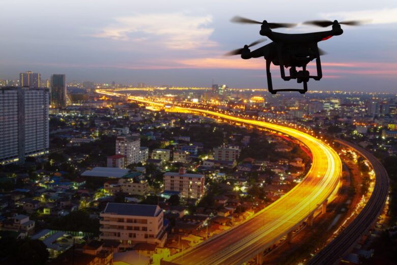 Picture of a drone flying over a major city at sunset.