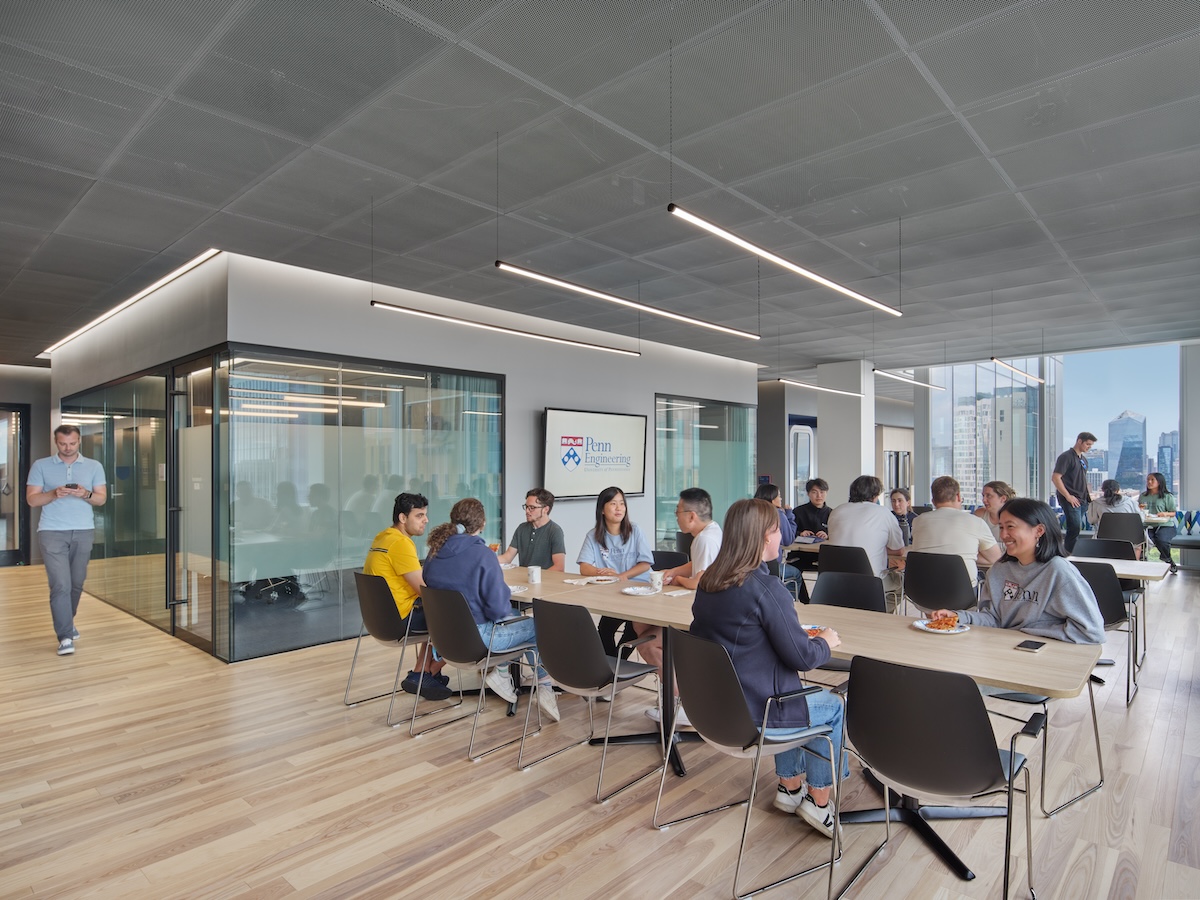 Dozens of researchers sit alongside one another and chat amicably in a cafeteria flooded with natural light.