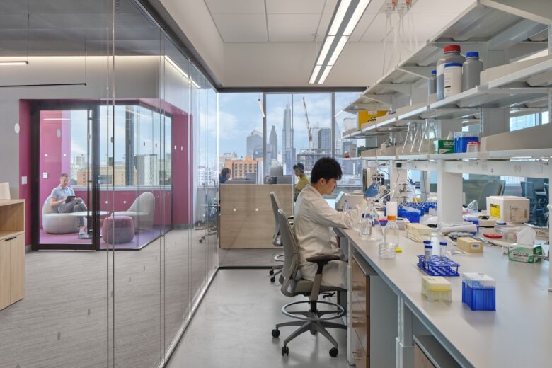 A group of researchers sit at lab benches and desks.