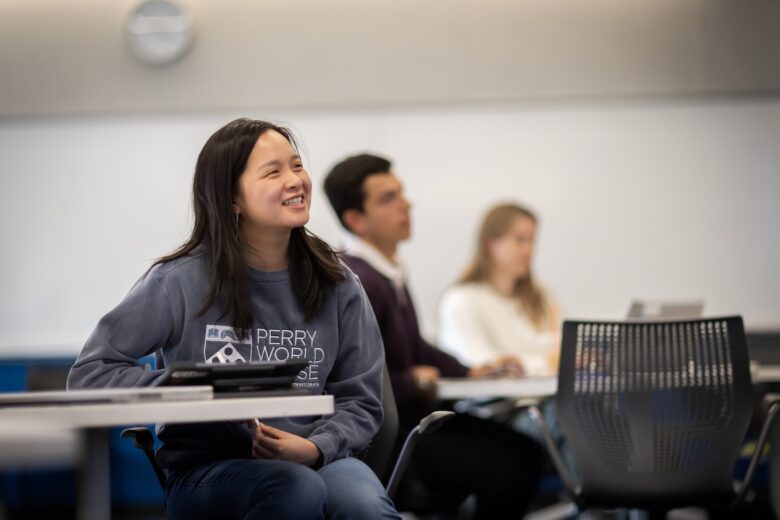 A student smiles while sitting at a desk.