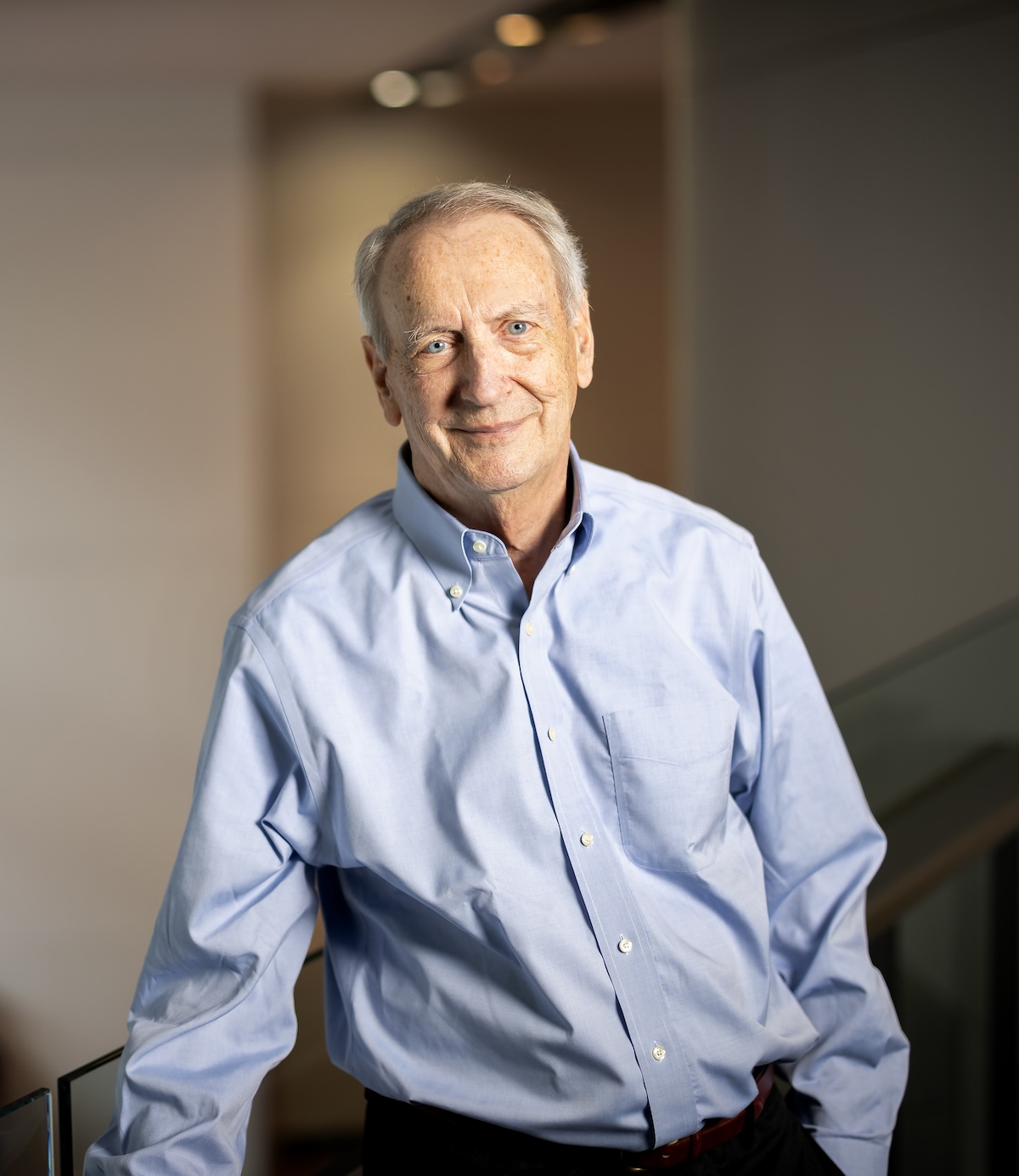 A man wearing a blue button-down shirt smiles at the camera.