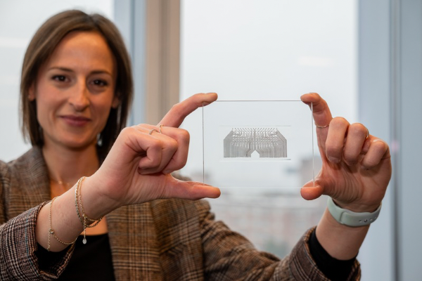 Picture of female Professor Flavia Vitale holding up an image of her skin sensor.