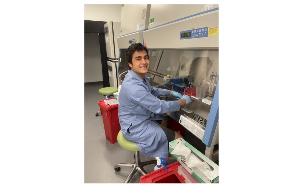 A picture of male student Ben Nachod ('26), a Bioengineering major,  sitting down on a chair working in a lab.