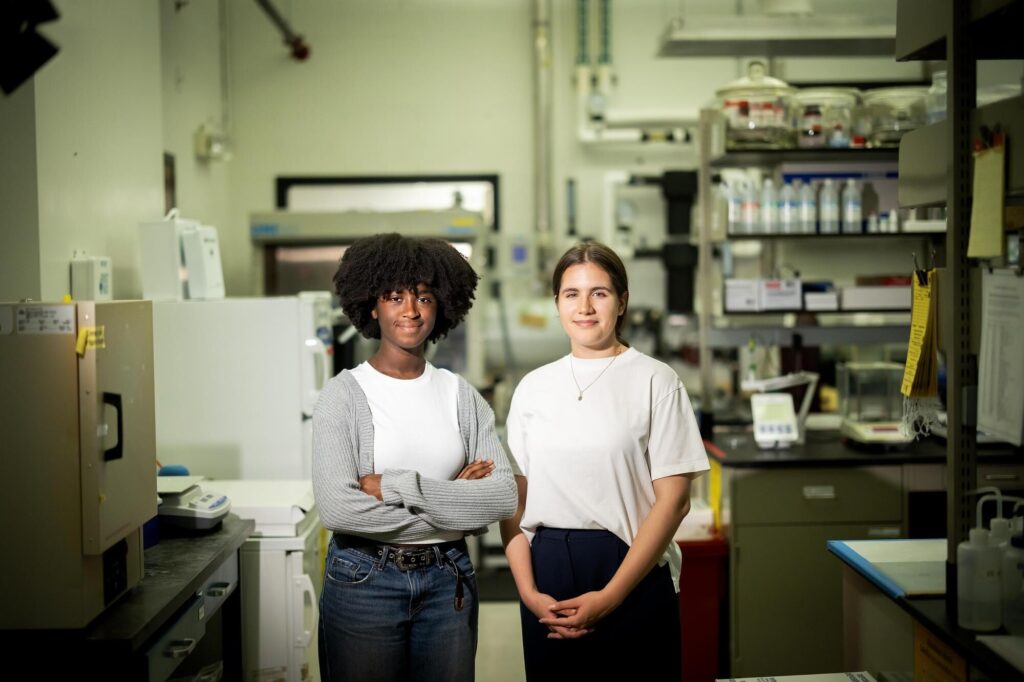 Picture of two female students in a lab. PURM Research - CoolSeal and Urban Heating - Angelica Dadda + Nafisa Bangura at the Laboratory for Research on the Structure of Matter.