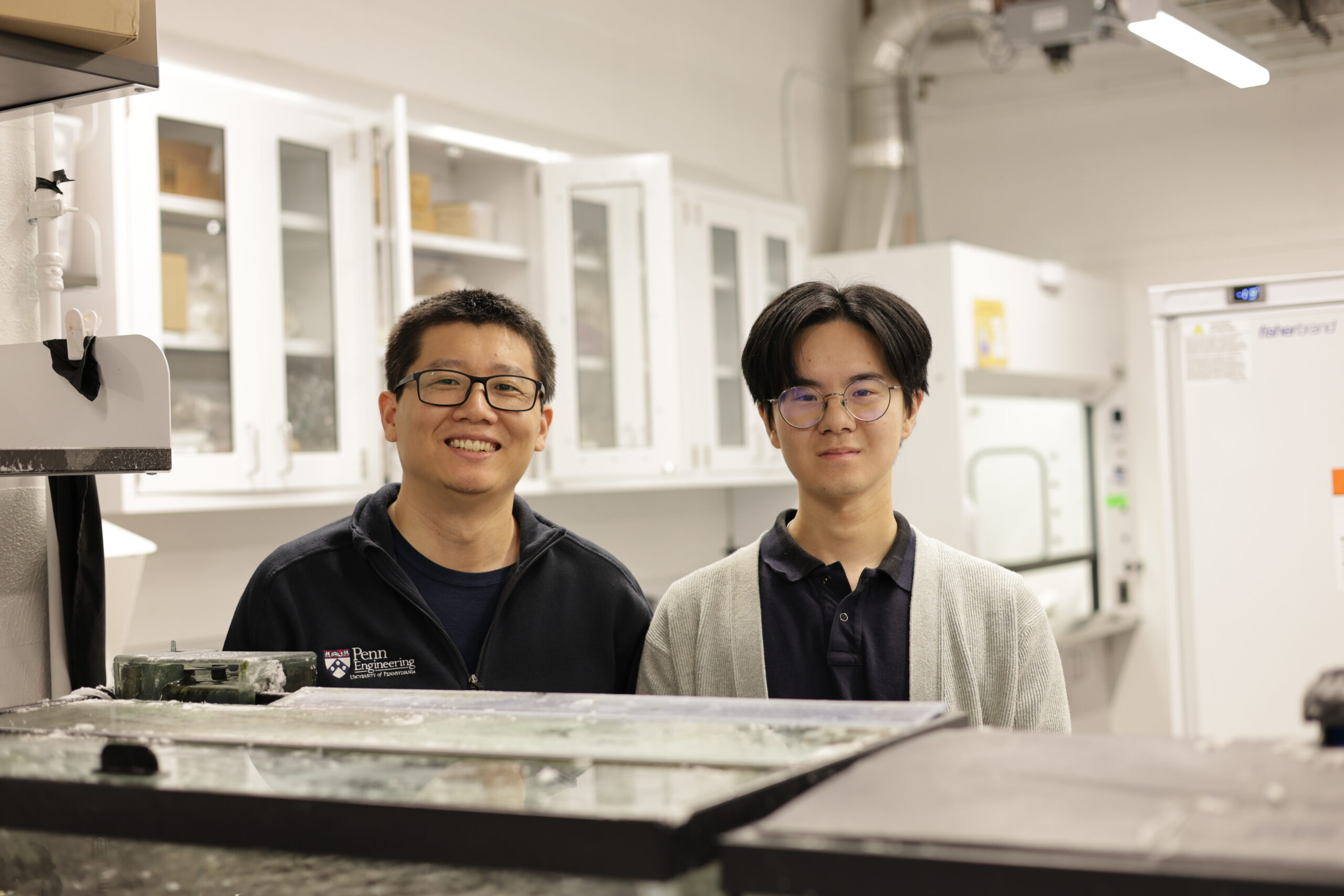 Two researchers stand side by side, behind an aquarium tank.